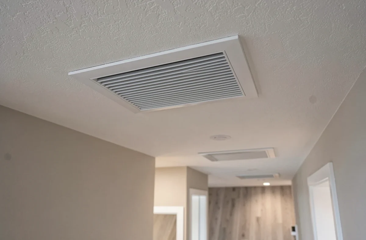 Grille de soufflage d'une pompe à chaleur gainable intégrée dans un plafond de couloir résidentiel rénové